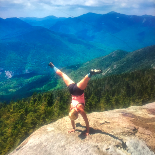 girl doing a cartwheel on top of a mountain